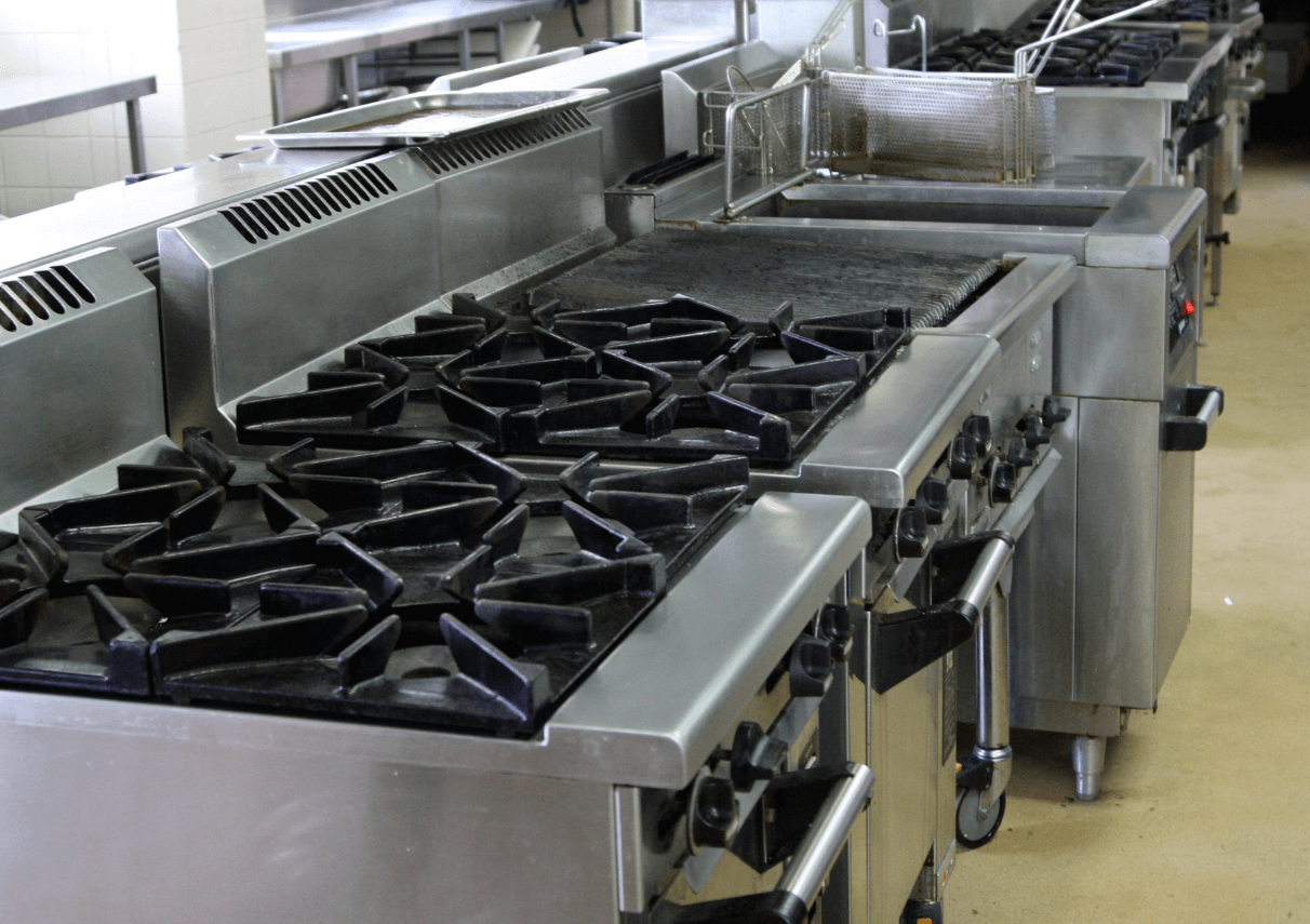 Commercial kitchen equipment repair service in Dubai restaurant showing technician servicing commercial cooking range and ventilation system