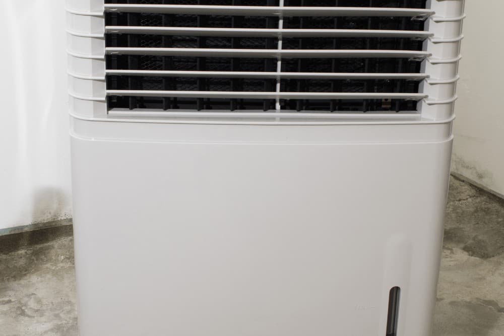Close-up of a white portable air cooler's front grille and horizontal louvre vents, photographed indoors