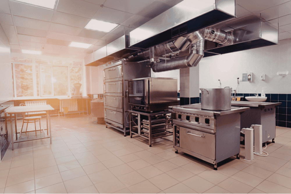 Commercial kitchen with a stainless steel extraction canopy, ductwork, ranges and ovens