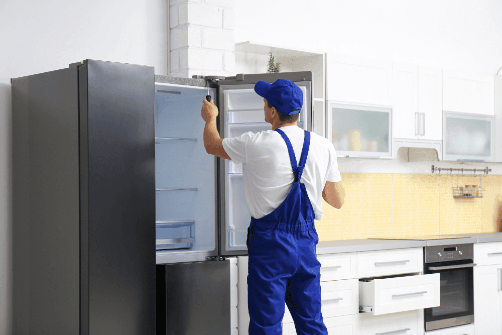Technician inspecting a kitchen refrigerator in a rented apartment