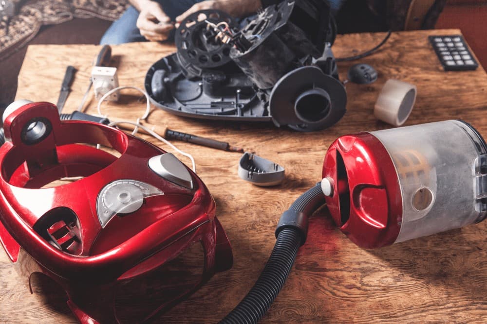 Vacuum cleaner's motor unit, dust canister and hose fully separated on a workbench for inspection during a fault diagnosis